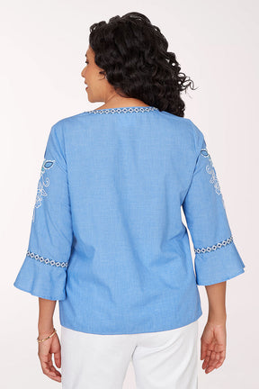 Woman wearing a blue embroidered blouse against a white background