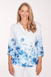 Woman wearing a white blouse with blue floral pattern on a white background