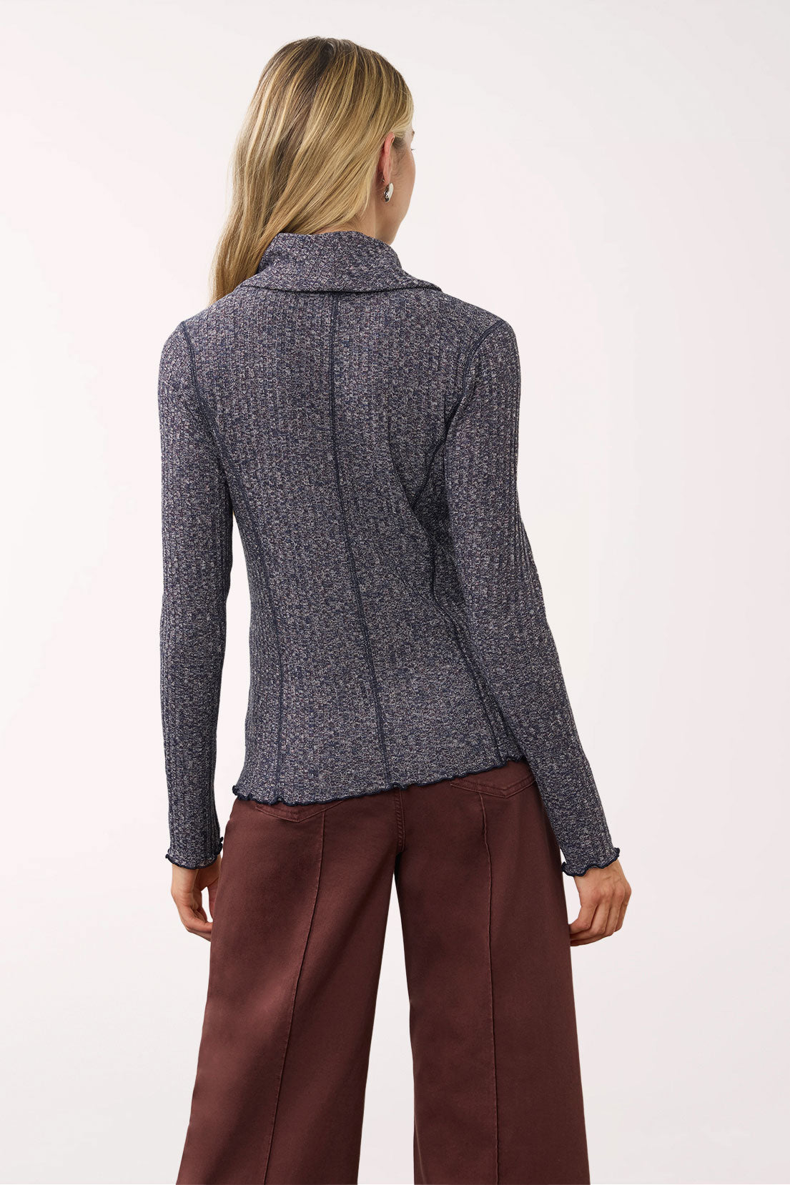 A woman shown from the back wearing a dark gray textured knit long-sleeve top and brown wide-leg trousers against a plain white studio background.