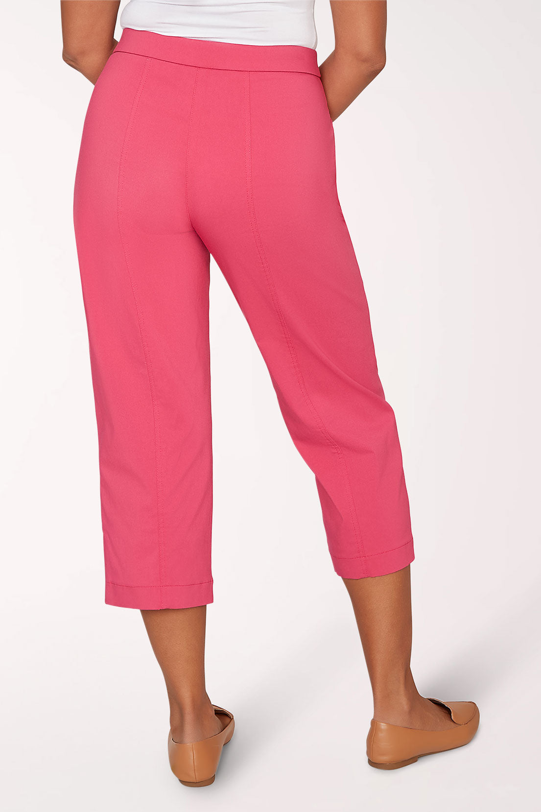 Person wearing bright pink capri pants on a white background