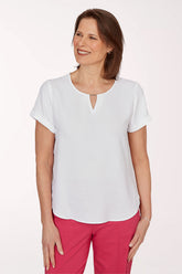 Woman wearing a white blouse and pink pants on a white background