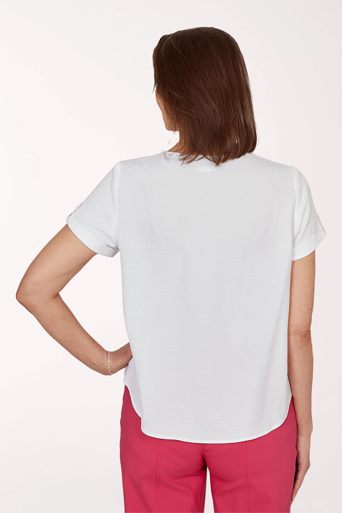 Woman wearing a white blouse and pink pants on a white background