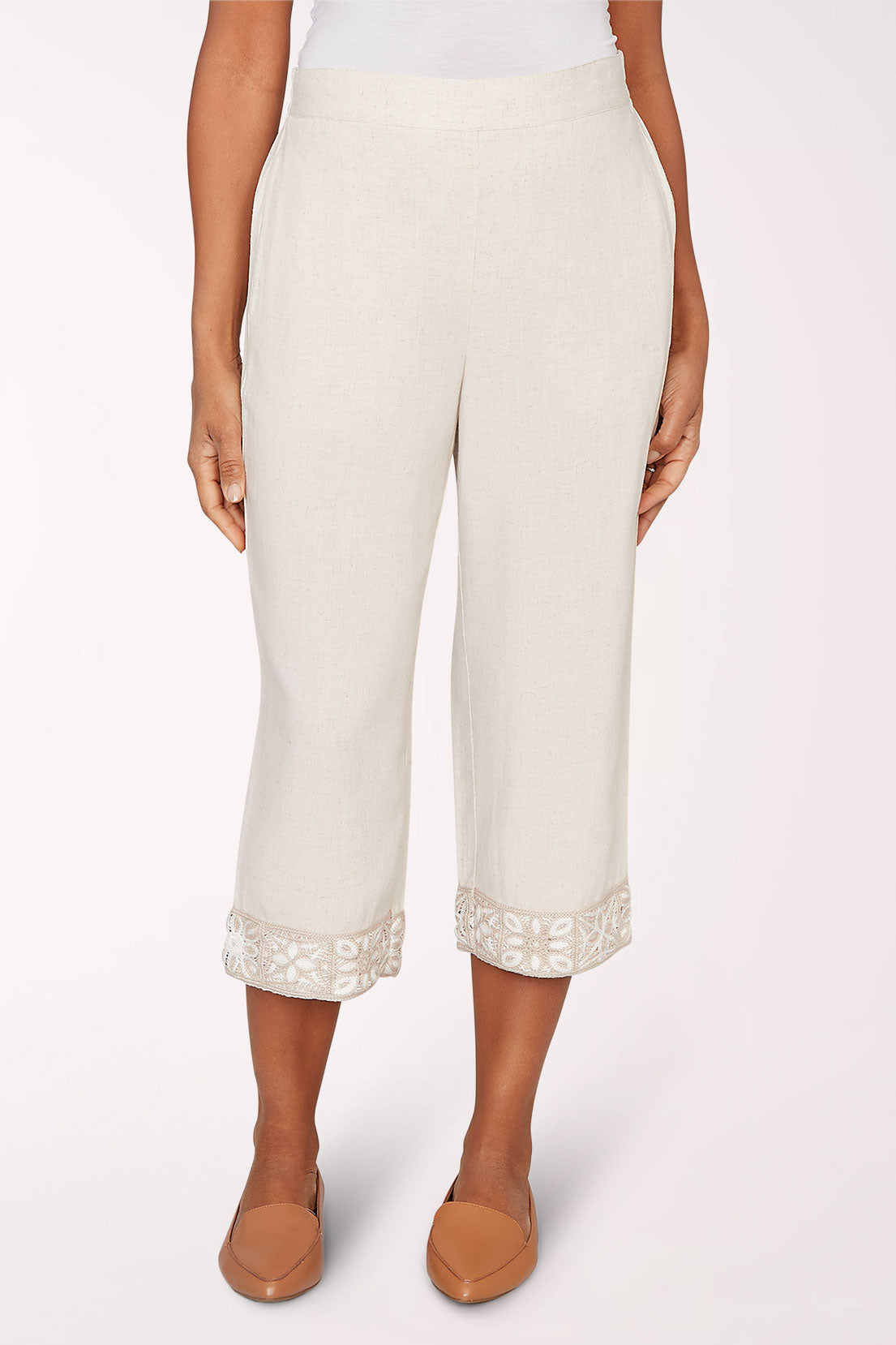 Person wearing white pants with lace cuffs on a white background