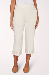 Person wearing white pants with lace cuffs on a white background