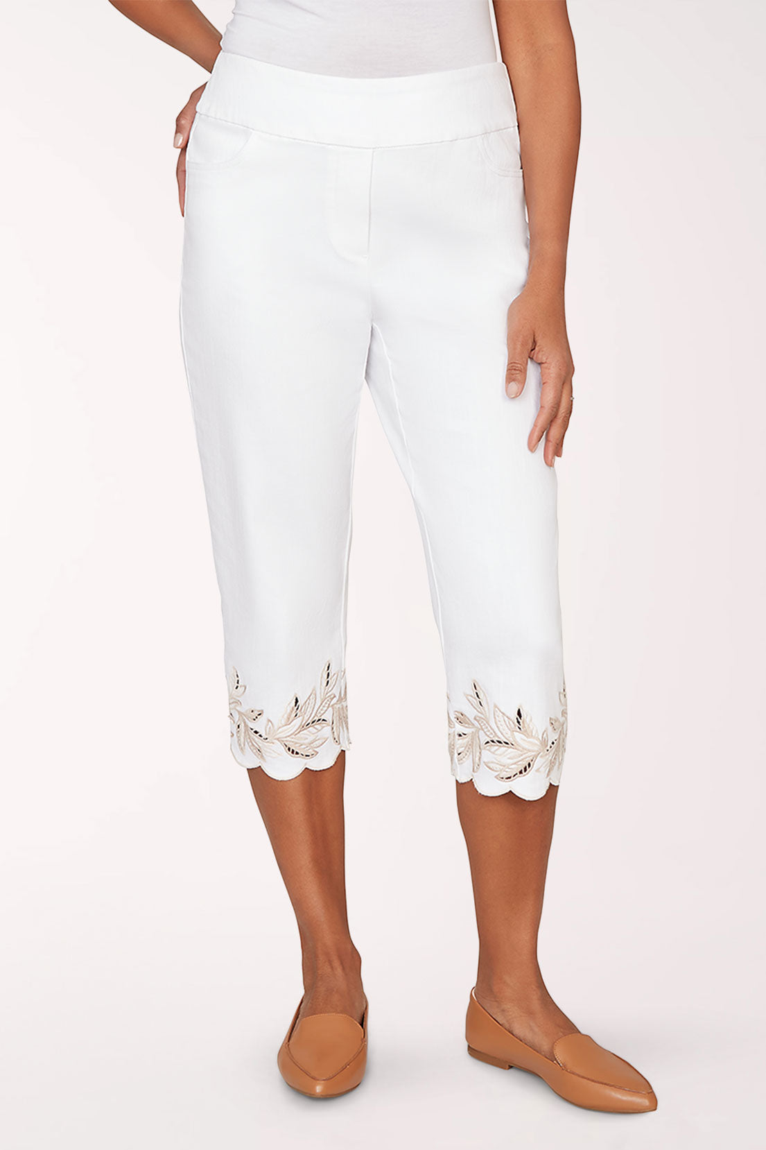 Person wearing white pants with lace trim and brown shoes on a white background