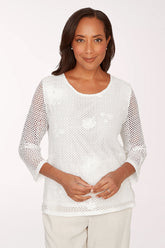 Woman wearing a white mesh top against a plain background