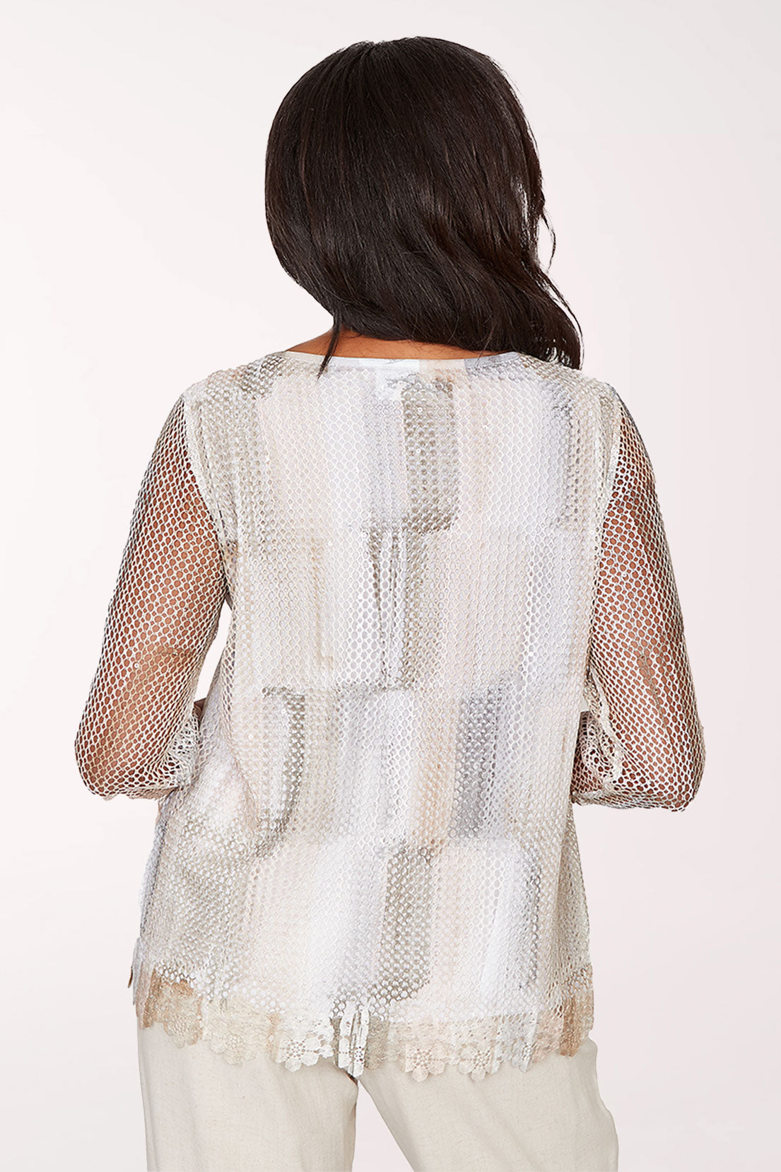 Woman wearing a sheer white top with a subtle pattern on a white background