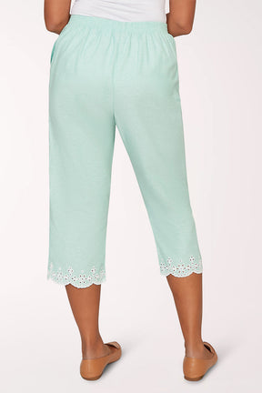 Mint green capri pants with lace trim worn by a person on a white background