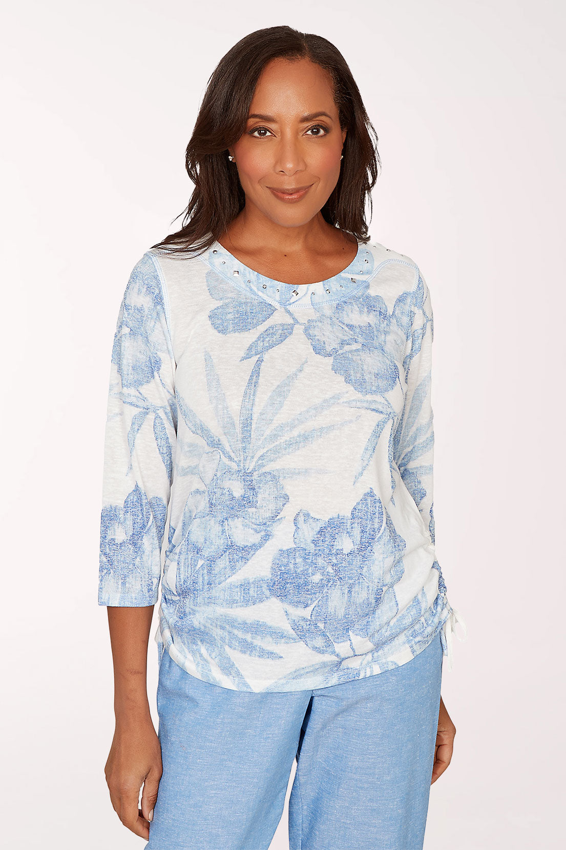 Woman wearing a blue and white floral blouse with light blue pants on a white background