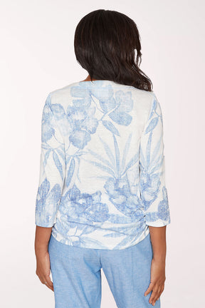 Woman wearing a blue and white floral blouse with light blue pants on a white background