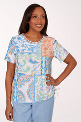 Woman wearing a colorful patterned top with a white background