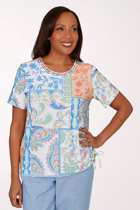 Woman wearing a colorful patterned top with a white background