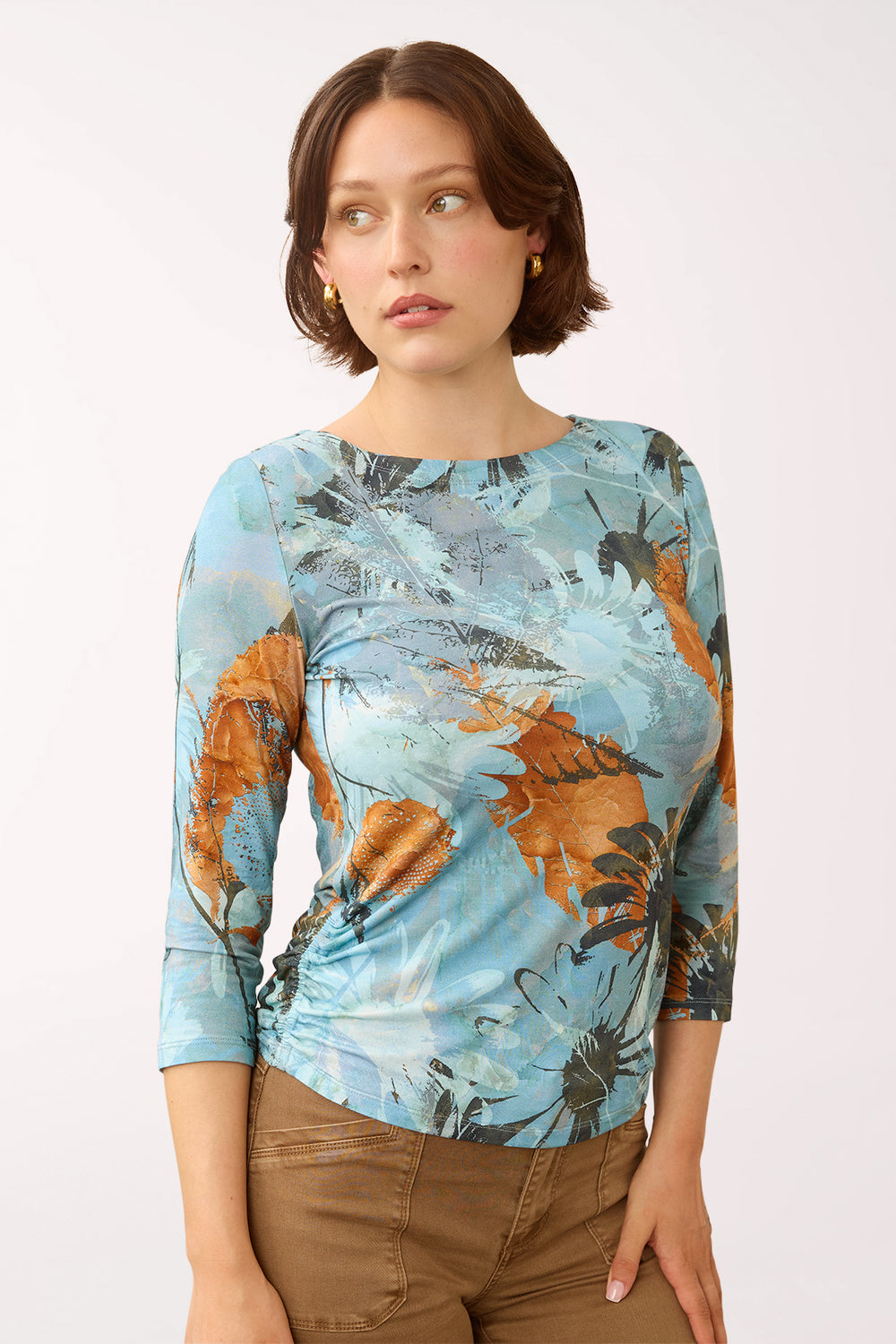 Woman wearing a 3/4 sleeve blue and multicolored top with a sunflower print