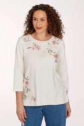 Woman wearing a white crochet top with a floral design