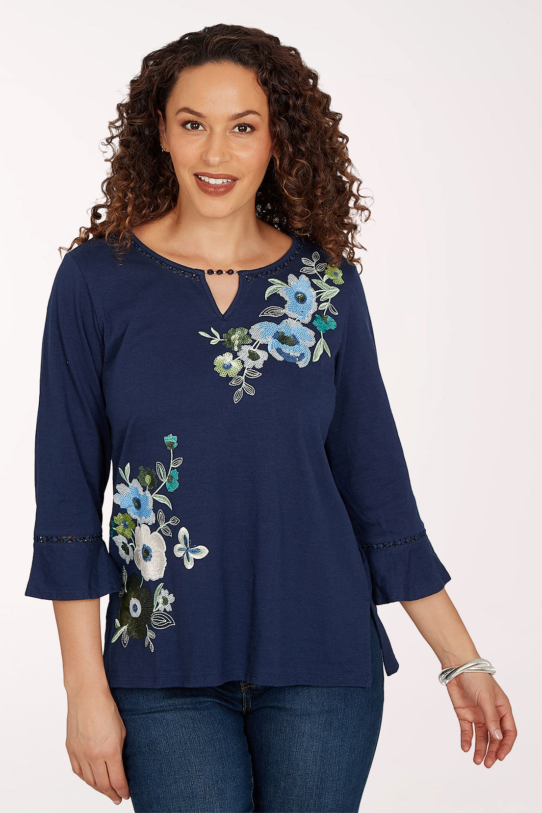 Woman wearing a navy 3/4 sleeve top with a floral design