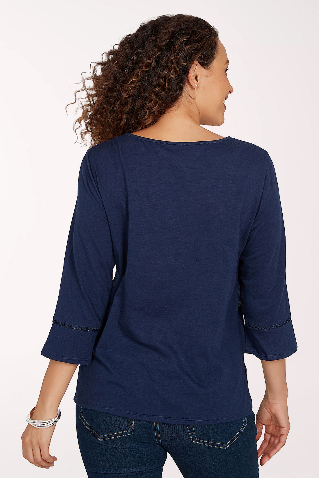 Woman wearing a navy 3/4 sleeve top with a floral design