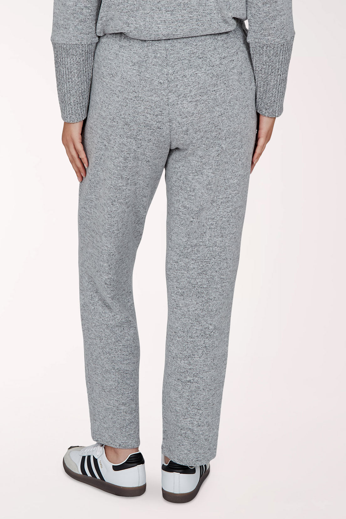 A person wearing heathered grey lounge pants with a matching long-sleeve top and white sneakers, shown from the waist down against a plain light background.