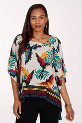 Woman wearing a colorful parrot and leaf patterned top on a white background