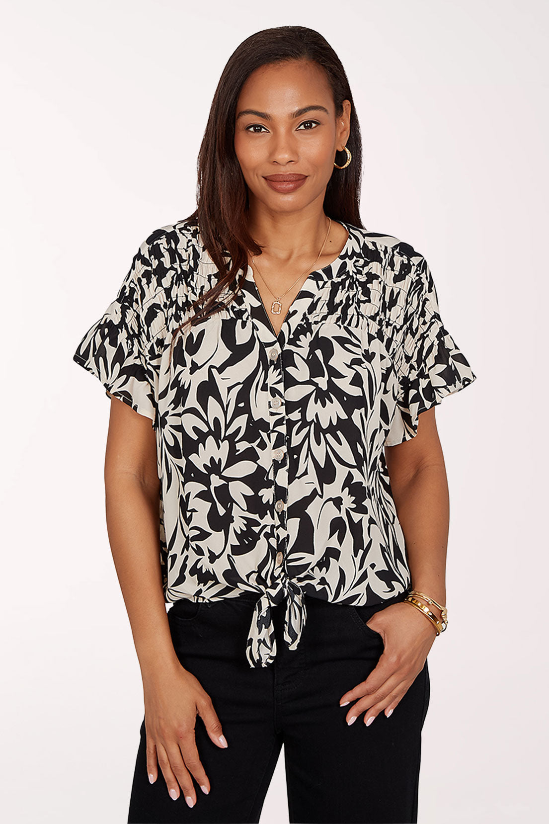 Woman wearing a black and white floral blouse with ruffled sleeves on a white background