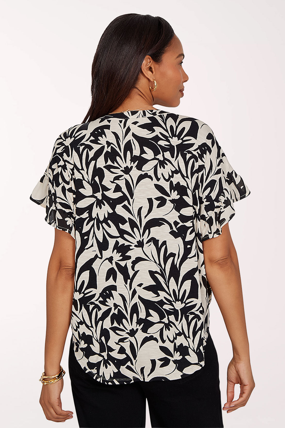 Woman wearing a black and white floral blouse with ruffled sleeves on a white background