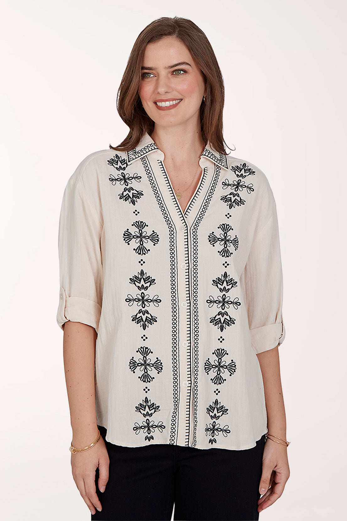 Woman wearing a white blouse with black embroidery on a white background