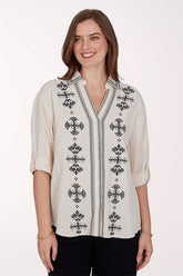 Woman wearing a white blouse with black embroidery on a white background