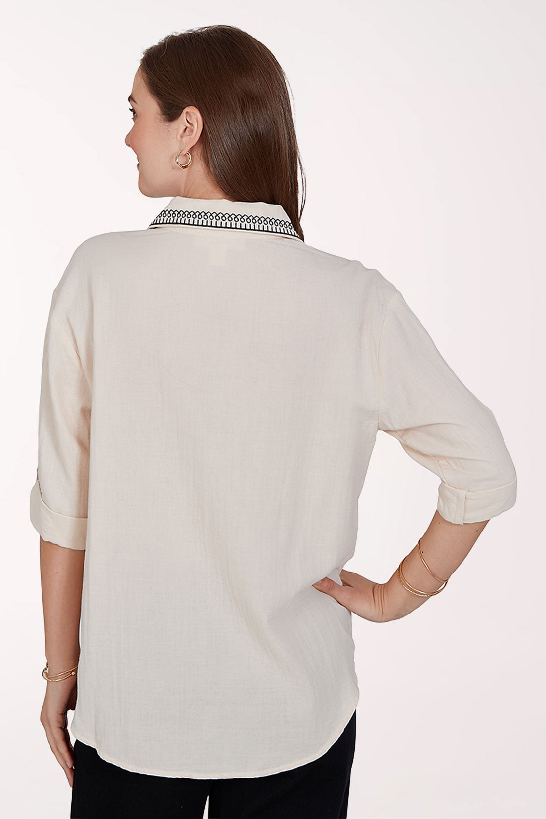 Woman wearing a white blouse with black embroidery on a white background