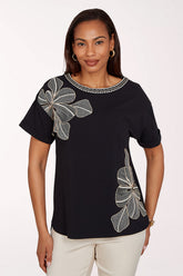 Woman wearing a black top with floral designs on a white background