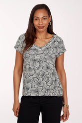 Woman wearing a black and white floral patterned top on a white background