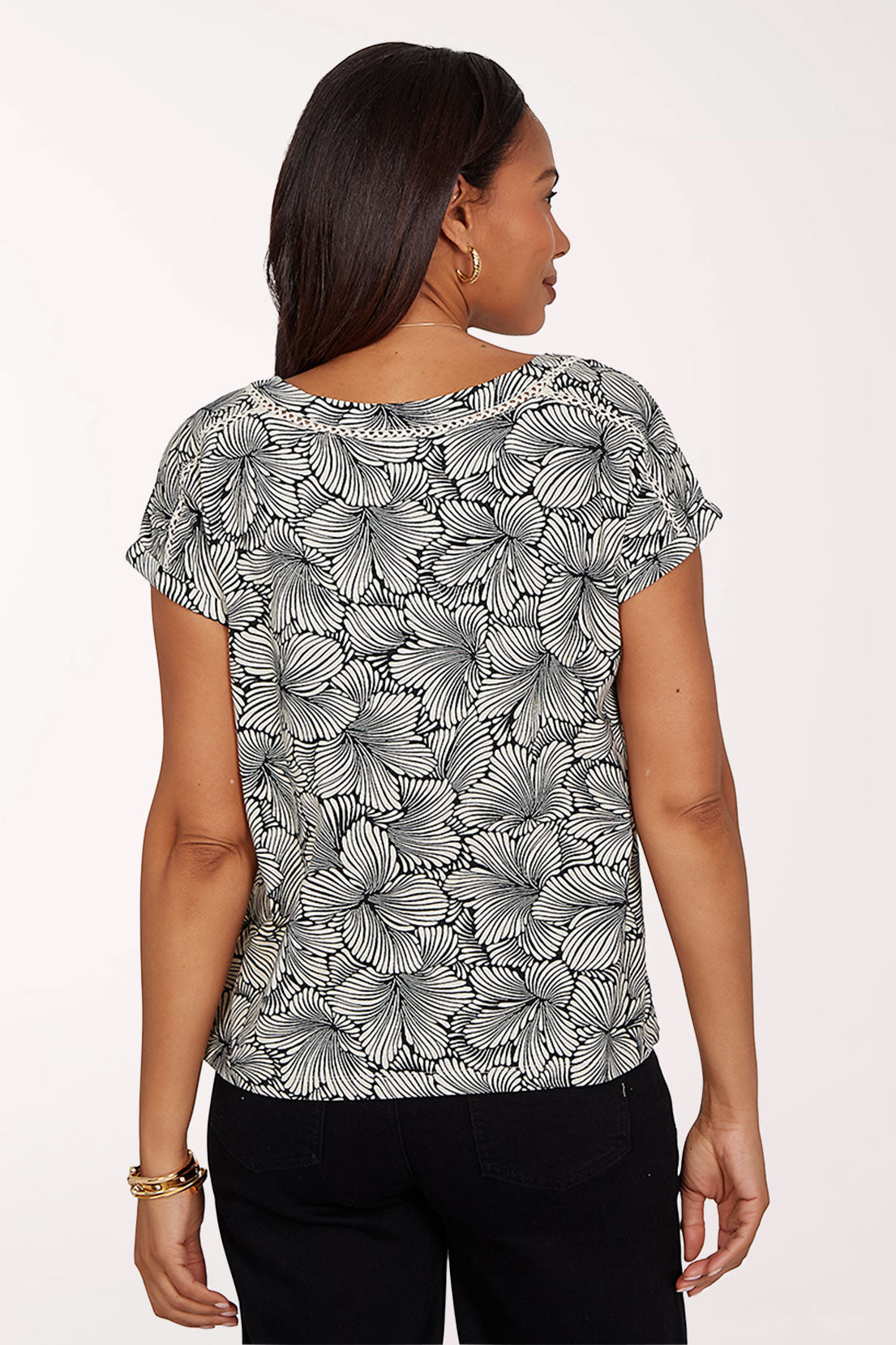 Woman wearing a black and white floral patterned top on a white background