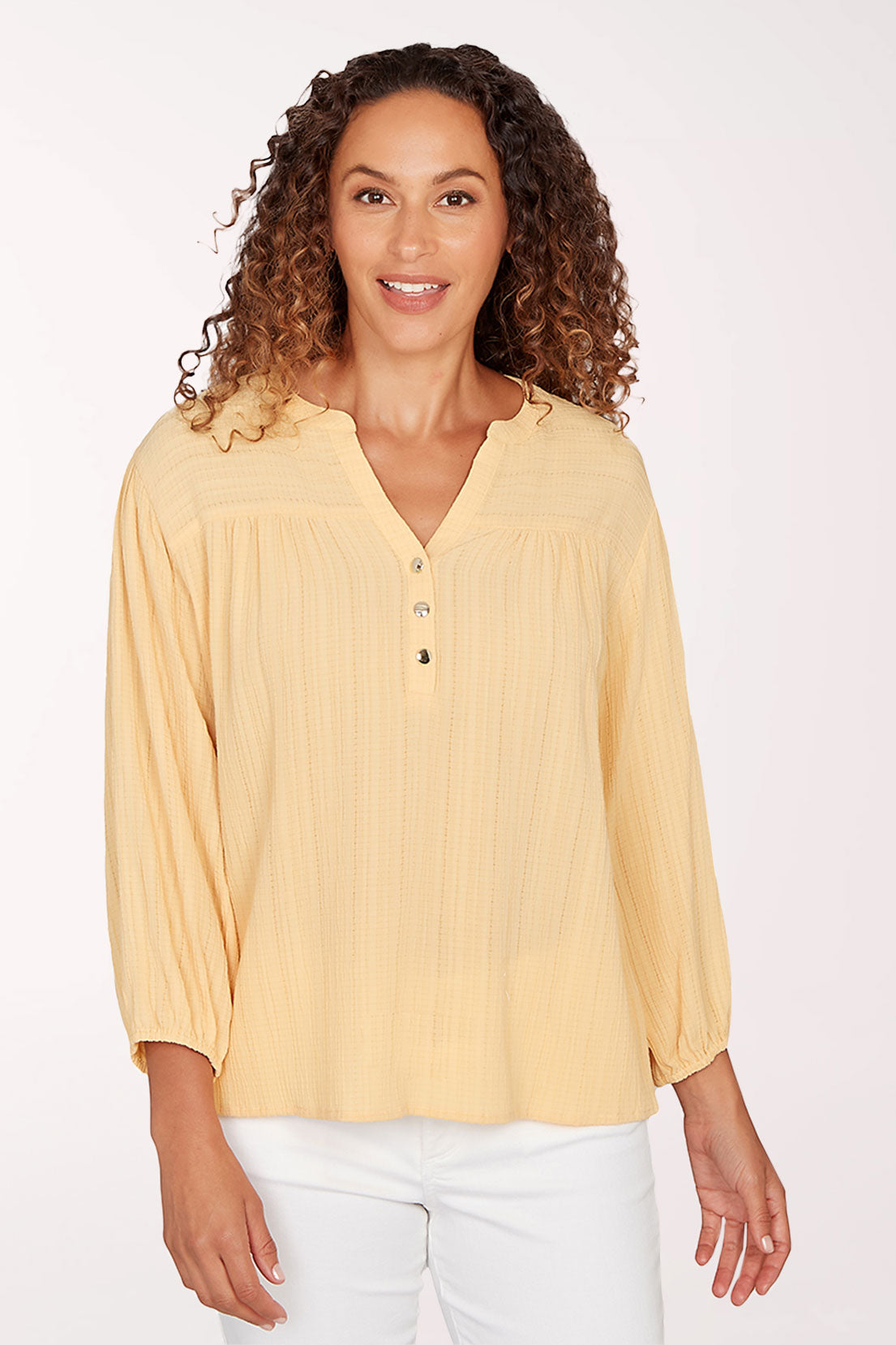 Woman wearing a yellow blouse with a plain background
