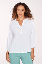 Woman wearing a white blouse with a subtle pattern on a plain background