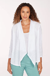 Woman wearing a white open-front cardigan over a white top and green pants on a light pink background