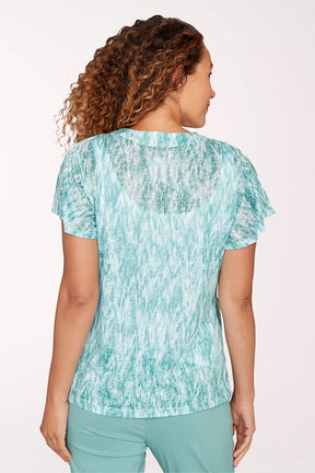 Woman wearing a teal patterned top and pants on a white background