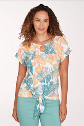 Woman wearing a short sleeve yellow and green leaf patterned top.