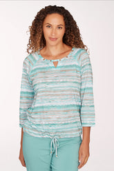 Woman wearing a striped long-sleeve top and light blue pants on a white background