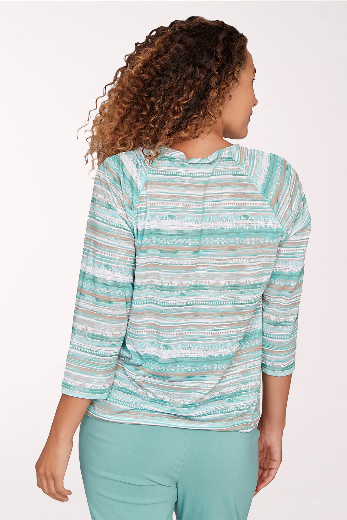 Woman wearing a striped long-sleeve top and light blue pants on a white background