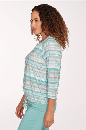 Woman wearing a striped long-sleeve top and light blue pants on a white background