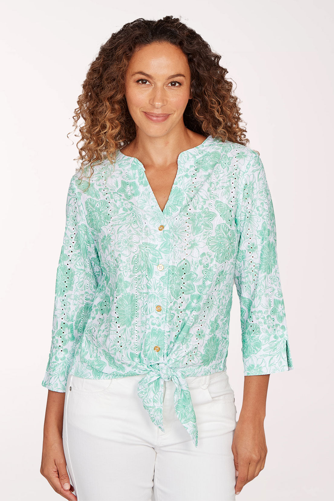 Woman wearing a light green floral blouse with a white background