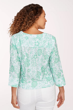 Woman wearing a light green floral blouse with a white background