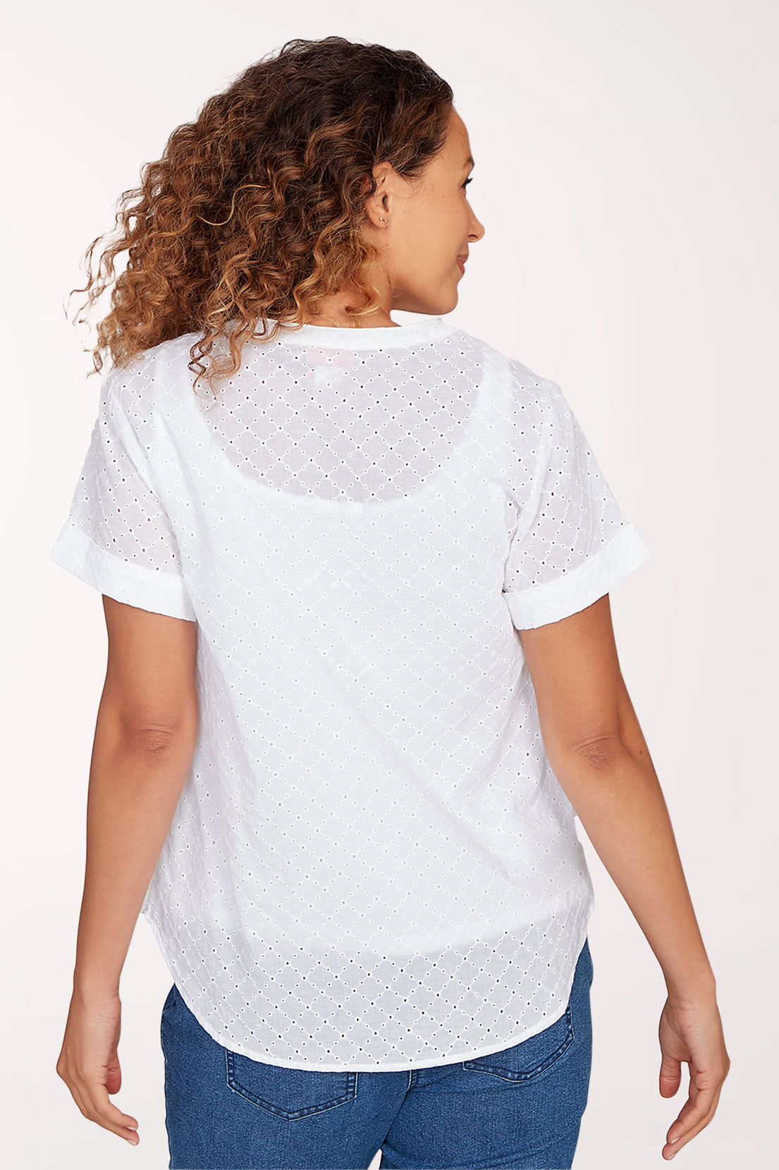 Woman wearing a white blouse with short sleeves and blue jeans on a white background