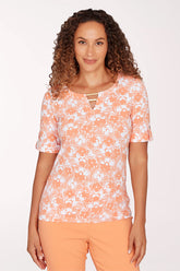 Woman wearing a floral patterned top and orange pants on a white background