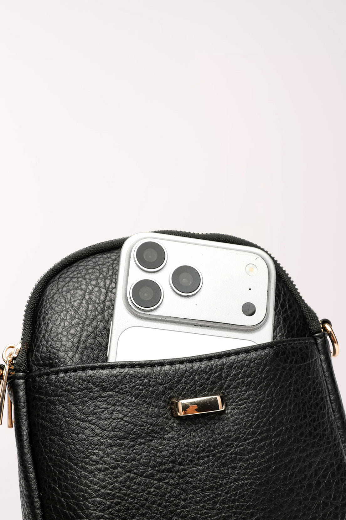 Close-up of the black 22 Tote Four-Pocket Crossbody Bag with a smartphone tucked into the front slip pocket.