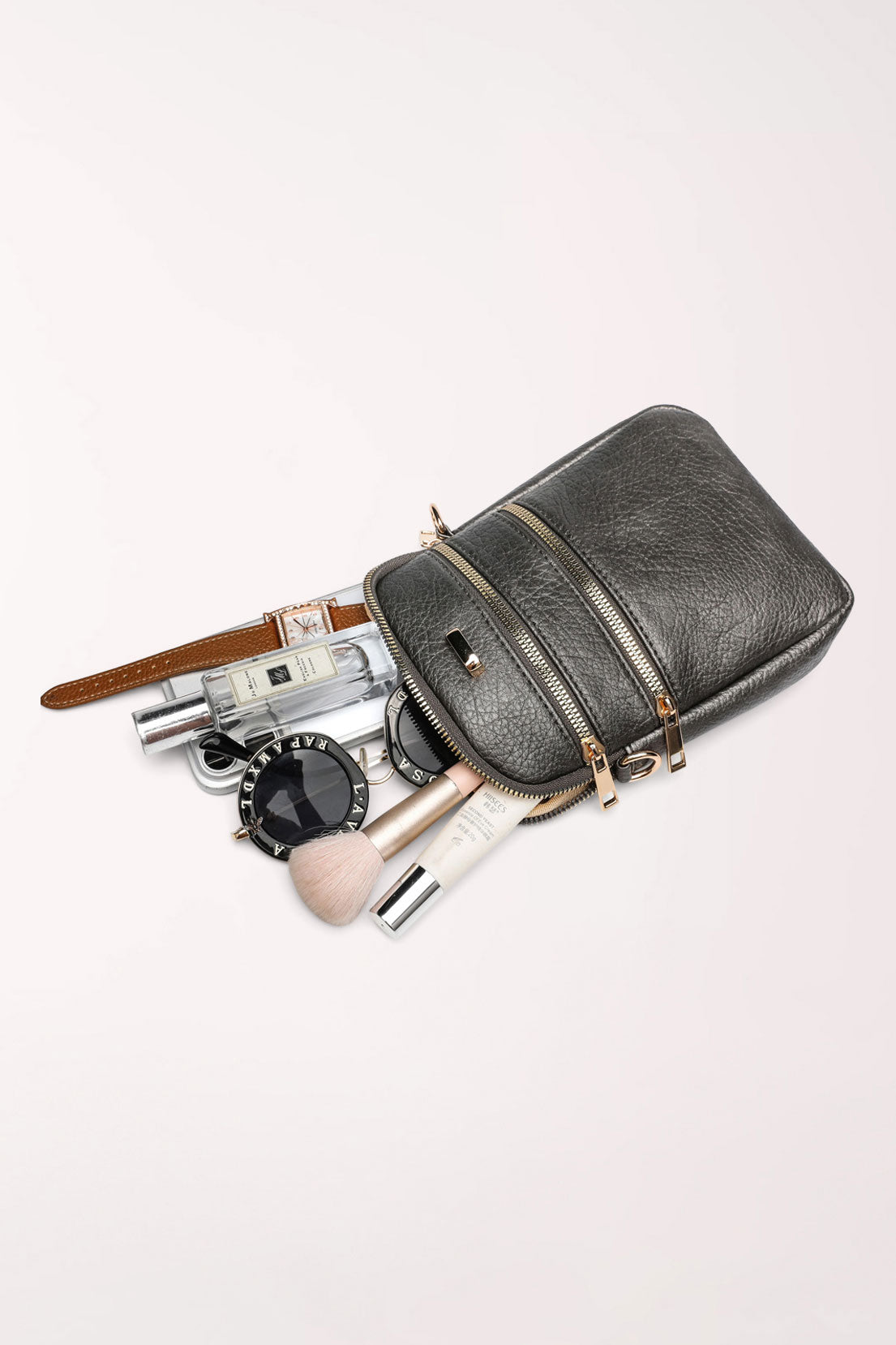 The pewter 22 Tote Three-Pocket Crossbody Bag lying flat with a phone, watch, perfume, compact mirror and makeup brush beside it to show what fits inside.