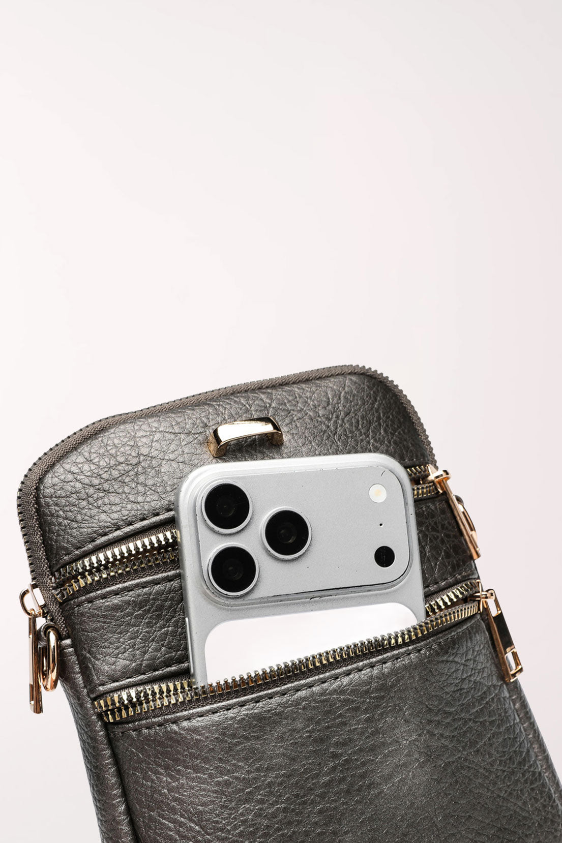 Close-up of the pewter 22 Tote Three-Pocket Crossbody Bag with a smartphone tucked into the upper front zip pocket.