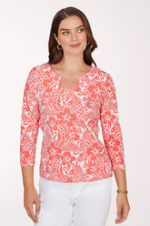 Woman wearing a coral floral patterned top on a white background
