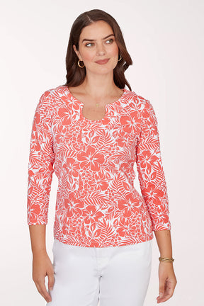 Woman wearing a coral floral patterned top on a white background