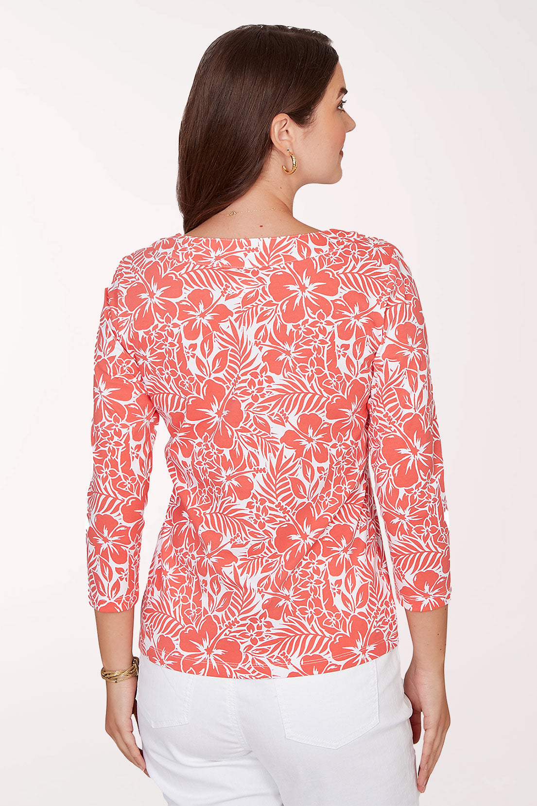 Woman wearing a coral floral patterned top on a white background