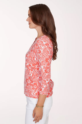 Woman wearing a coral floral patterned top on a white background