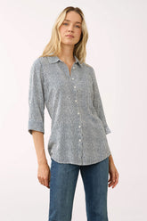 A woman modeling a long-sleeve button-up shirt with a fine vertical stripe pattern in gray and white, paired with blue jeans, against a plain light background.